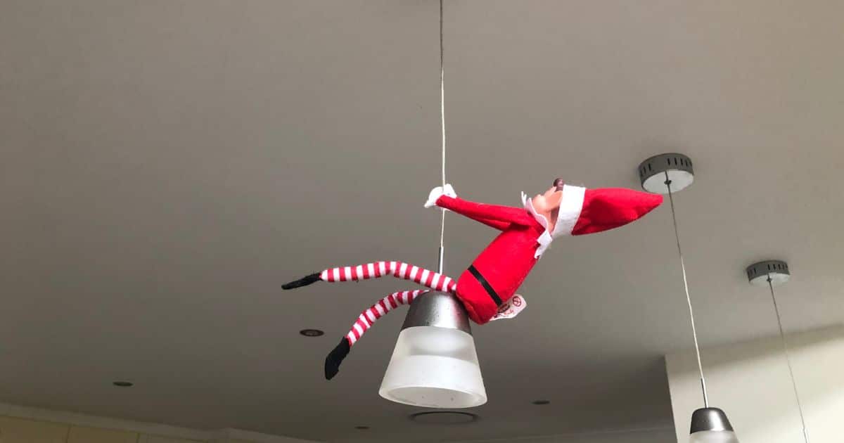 christmas elf hanging from a light.